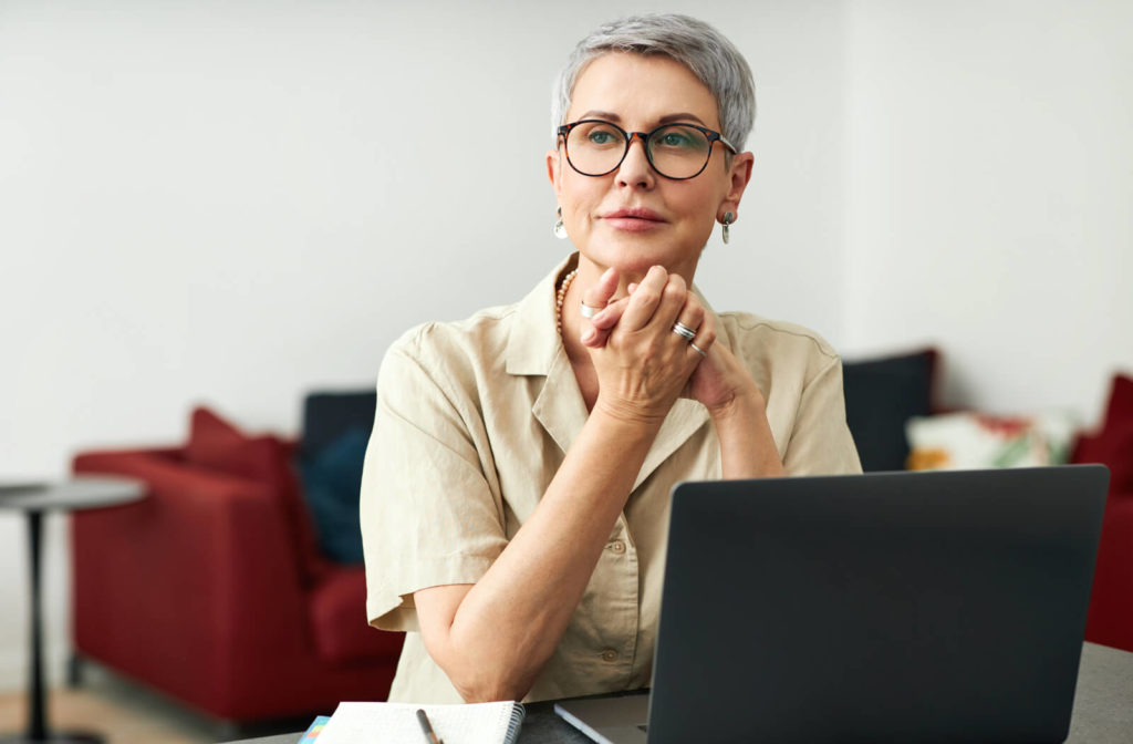 An older woman working at her laptop with computer glasses on