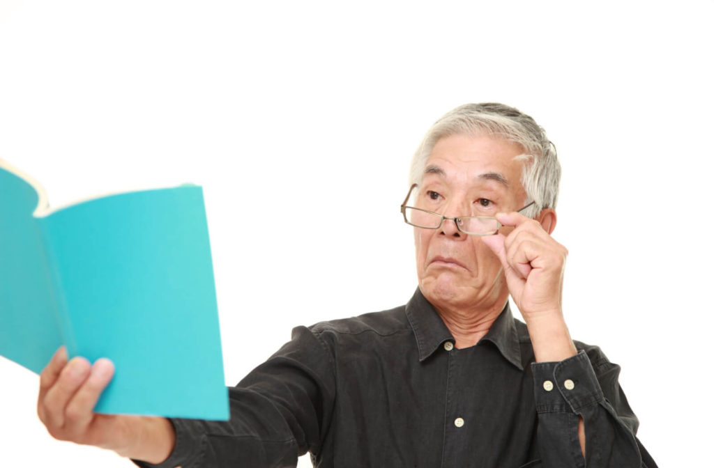 A senior male is reading a book at a far distance