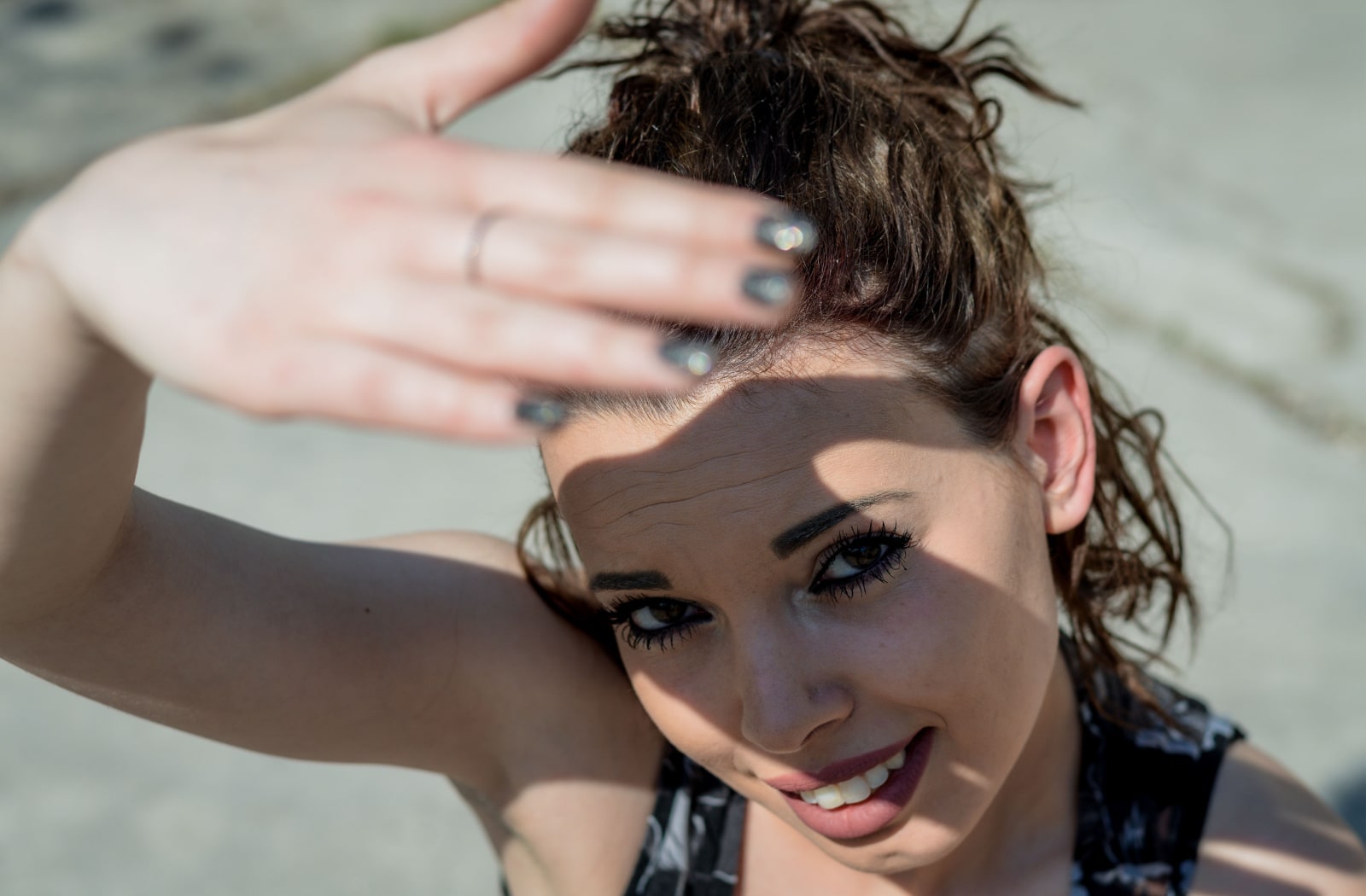 A woman uses her hand to block bright sunlight from her vision.