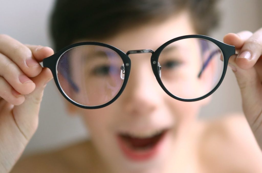 An excited boy shows off eyeglasses that will correct his myopia and allow for clear vision.