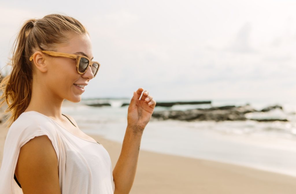 A woman wears her sustainable wood sunglasses on the beach.