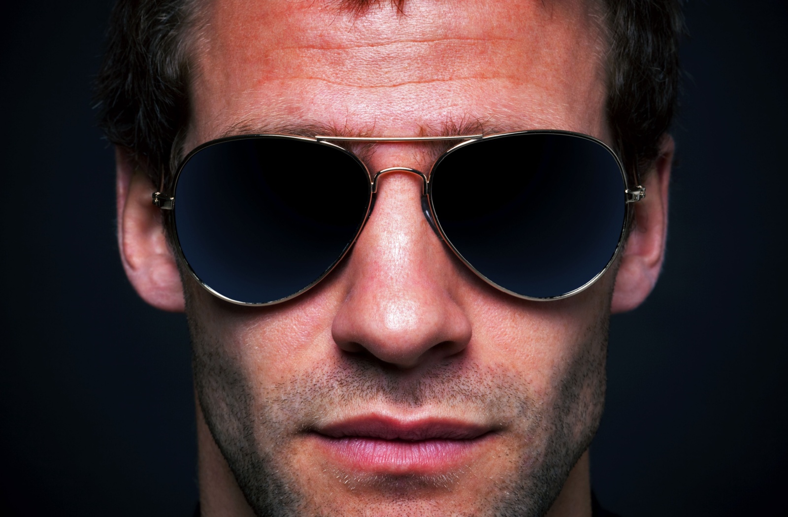 A close-up of a man wearing classic aviators sunglasses.