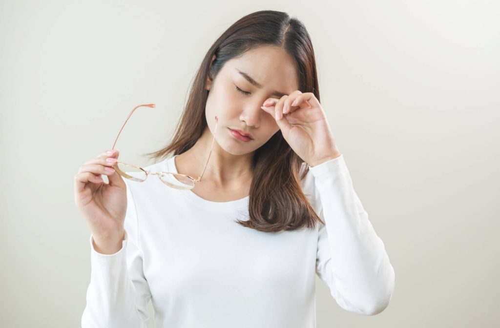 A young adult rubbing thier dry eyes.