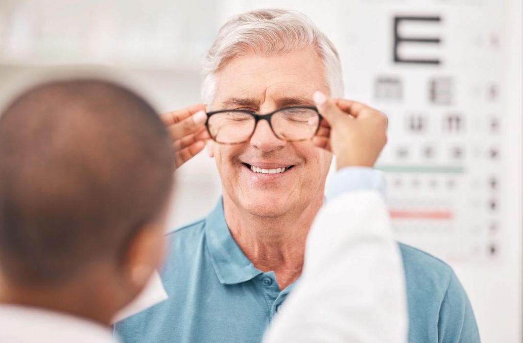 A senior adjusting eyeglasses with the help of an eye care professional during a vision exam.